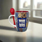 A ceramic coffee mug featuring a vibrant, detailed tile pattern with the word "Portugal" boldly displayed. This delightful keepsake comes with a red plastic spoon that fits neatly through a hole in the handle, resting along the side of the mug.