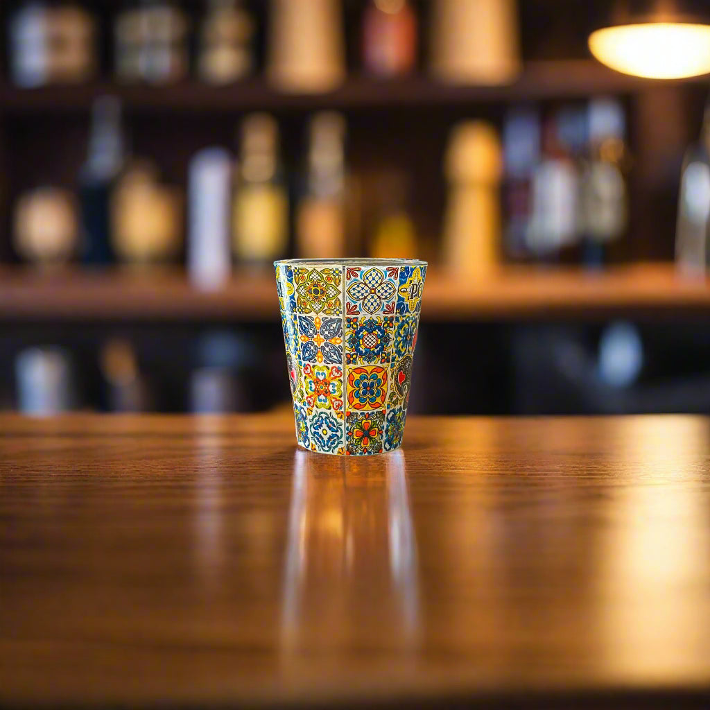 Portugal shot glass decorated with traditional Portuguese azulejo tiles displayed on a wooden bar counter with blurred background.