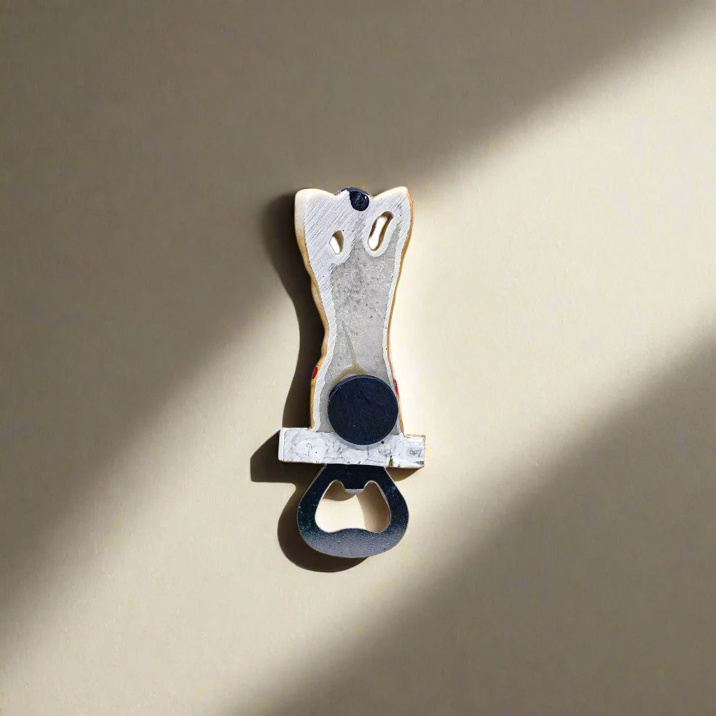 A white and black bottle opener topped with a figurine of a muscular man in red swim briefs and sunglasses, hands casually behind his head. This eye-catching "Portugal man" serves as both a souvenir and a functional opener.