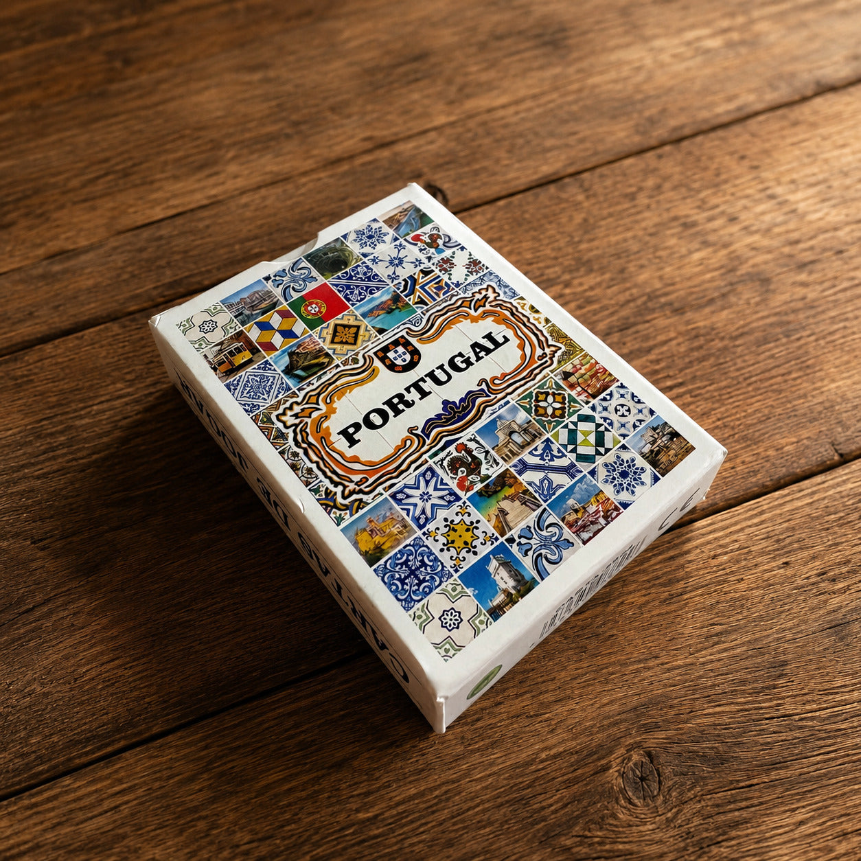 Angled view of a Portugal souvenir playing cards box on a rustic wooden surface, decorated with colourful azulejo motifs and iconic Portuguese imagery.