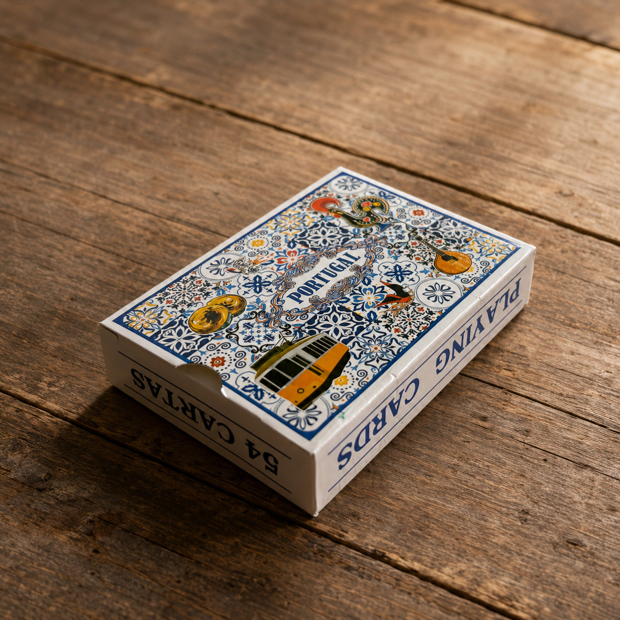 Angled view of Portugal playing cards souvenir box on a wooden table, featuring 54 cards and a colourful design inspired by Portuguese azulejo tiles and cultural icons.