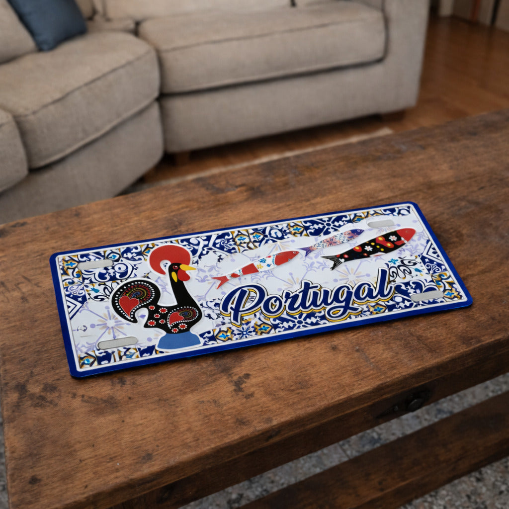Portugal metal souvenir sign placed on a wooden table showing Barcelos rooster, stylized sardines and classic Portuguese tile design