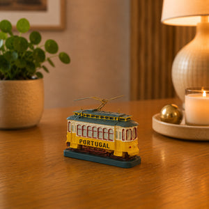 Portugal traditional yellow tram souvenir figurine displayed on a wooden table, inspired by Lisbon’s iconic vintage tram and photographed in a cozy home interior.