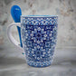 Featuring a design of blue and white traditional Portuguese tiles, this ceramic coffee mug displays the word "PORTUGAL" around the bottom. It includes a blue spoon that tucks into a slot on the handle, making it a charming and practical keepsake.