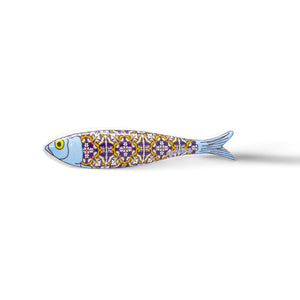A stylized fish sculpture, resembling a Portugal sardine, features a blue head and an intricately patterned body in yellow, white, and purple. With a single large yellow eye and a light blue tail that fades into the background, this vibrant design doubles as an exquisite magnet.