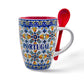 A decorative ceramic coffee mug with intricate colorful floral patterns reminiscent of traditional tile design and the word "PORTUGAL" in blue letters. This souvenir features a red interior and comes with a matching red spoon inserted through the handle.