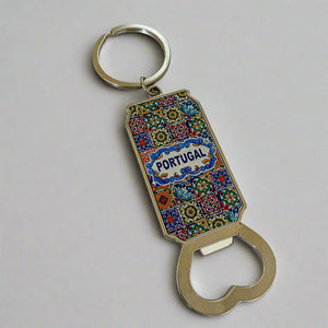 A keychain bottle opener adorned with a vibrant tile pattern and "Portugal" prominently displayed in the center. The intricate design blends geometric and floral elements in bright, lively colors. This practical souvenir features a circular keyring at the top and a sturdy metal opener at the bottom, combining functionality with a touch of Portuguese charm.
