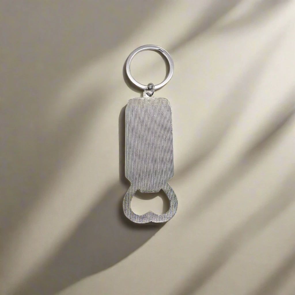 Keychain bottle opener with a rectangular silver body and a circular keyring at the top, casting a shadow on a light beige surface. Perfect for adding a touch of Portugal to your everyday essentials.
