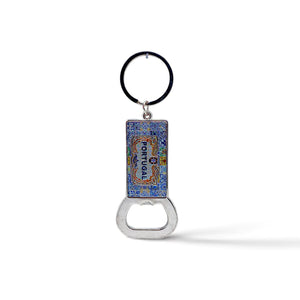 A souvenir keychain with a blue and colorful enamel rectangular pendant featuring intricate designs and the word "PORTUGAL." Attached to the pendant is a handy bottle opener at the bottom. The keychain ring is black.