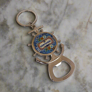 A metal keychain shaped like a ship's wheel and anchor, featuring a vibrant design in the center with the word "Portugal." The keychain includes a bottle opener at the base and a magnet on the back, combining functionality with a nautical-themed souvenir charm.