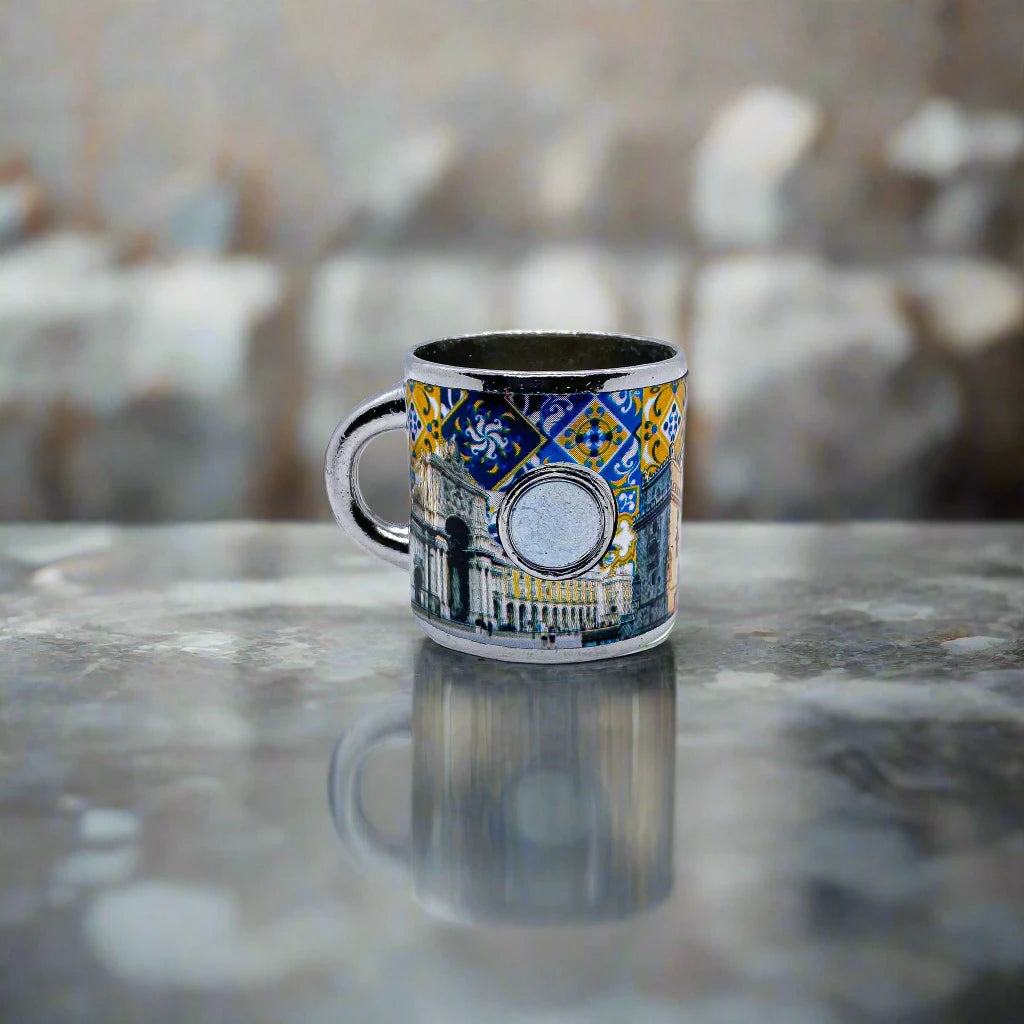 This colorful ceramic mug highlights detailed and vibrant depictions of Portuguese landmarks, traditional patterns, and a crest. The word "Portugal" is prominently centered, making it a standout souvenir. The metallic silver finish on the handle and rim gives the mug a refined and unique look.