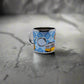 This small metal mug features "Portugal" prominently displayed on a blue and white background, styled like traditional Portuguese tiles. Colorful illustrations, such as the famous Portuguese rooster, add a playful touch, making it a perfect keepsake to complement your Portugal-themed magnet collection.
