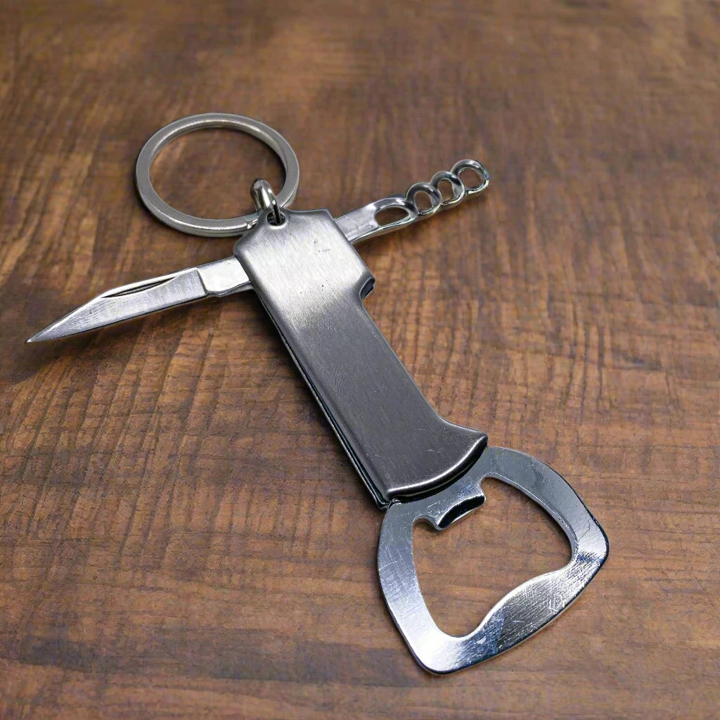 A practical multi-functional keychain displayed on a wooden surface. This Portugal souvenir includes a small metal knife blade, a corkscrew, and a bottle opener. The keyring is securely attached to the top, ready for use.