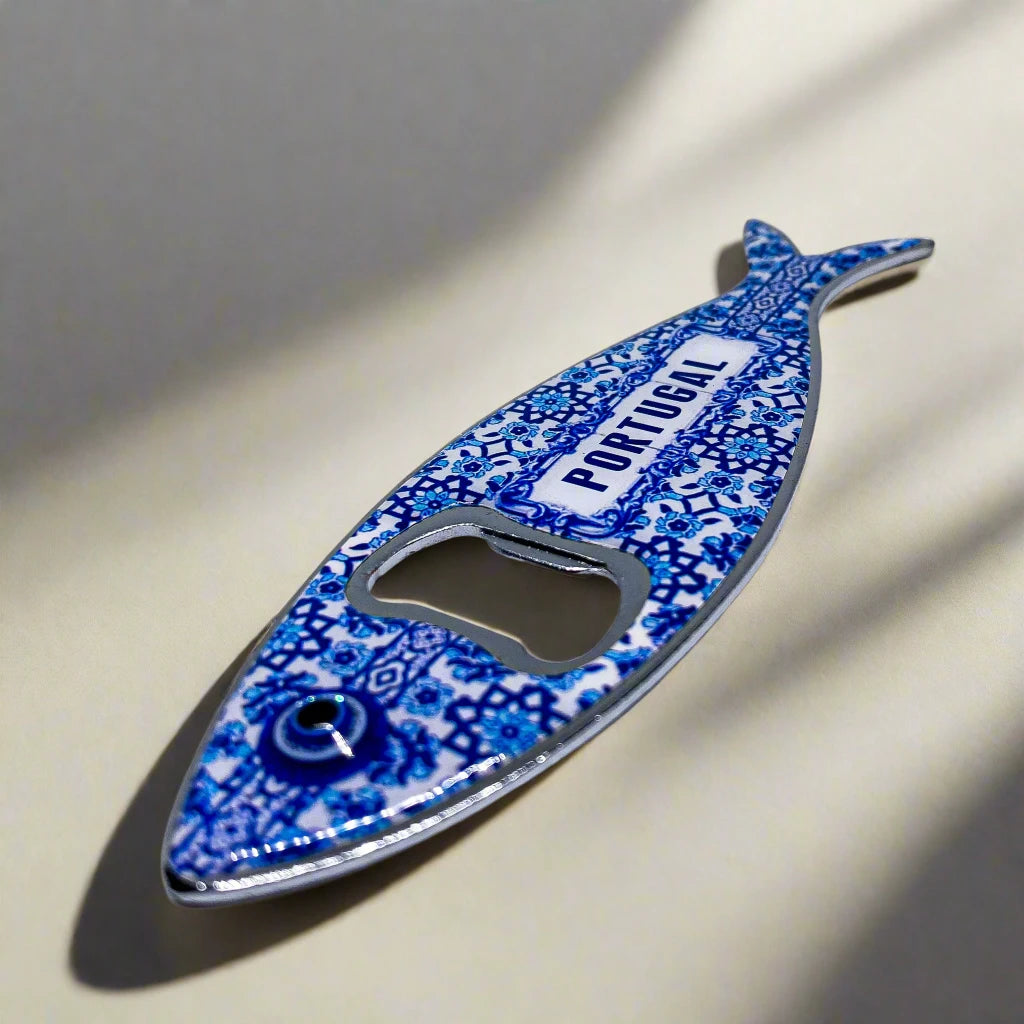 A metal bottle opener shaped like a fish, featuring vibrant, intricate patterns. The word "PORTUGAL" is boldly displayed in blue on the sardine’s body. This versatile souvenir also functions as a magnet, perfect for displaying on your fridge.