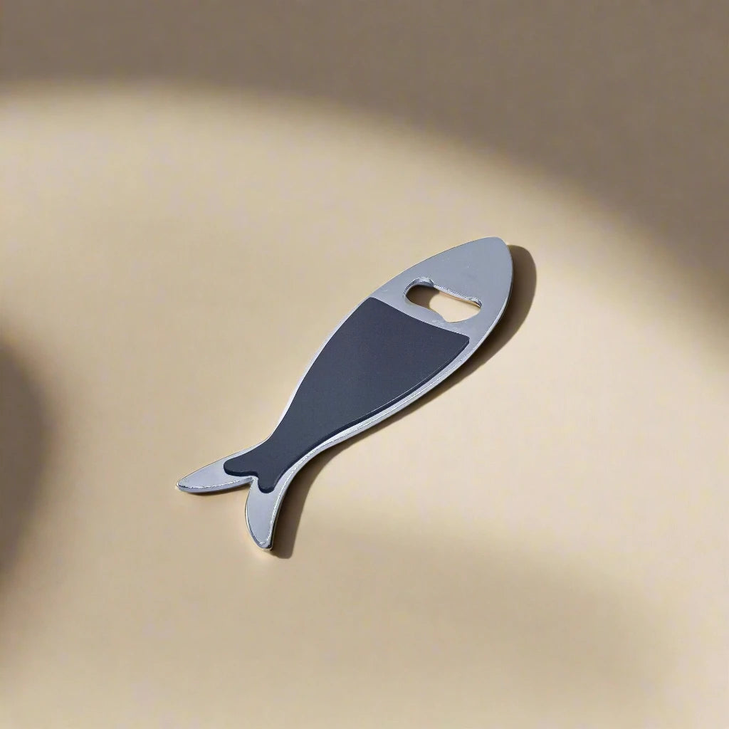 A fish-shaped metal bottle opener, styled as a sardine, features vibrant, detailed designs with a Lisbon landmark and the word "Lisboa." The opener hole is cleverly integrated where the fish’s eye would be, making it a charming Portuguese souvenir.