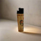 A souvenir lighter adorned with traditional Portuguese artwork, including a vibrant rooster and the word "PORTUGAL" displayed prominently. The lighter features a black top.