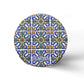 A round cork coaster displays a colorful, intricate tile pattern featuring blue, yellow, and green designs. The word "Portugal" is written near the bottom in a decorative font. The background is white and minimalistic. This charming item makes for a perfect souvenir from Portugal.