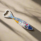 A fish-shaped metal bottle opener featuring a heart-shaped handle and a detailed, colorful cityscape design across the body, showcasing buildings and landmarks inspired by Portugal. The opener's primary color is blue, and it includes a magnet on the back for convenient display, making it a charming and functional souvenir.