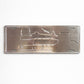 Backside of Serra da Estrela metal souvenir sign showing engraved mountain and building outlines on a metallic surface