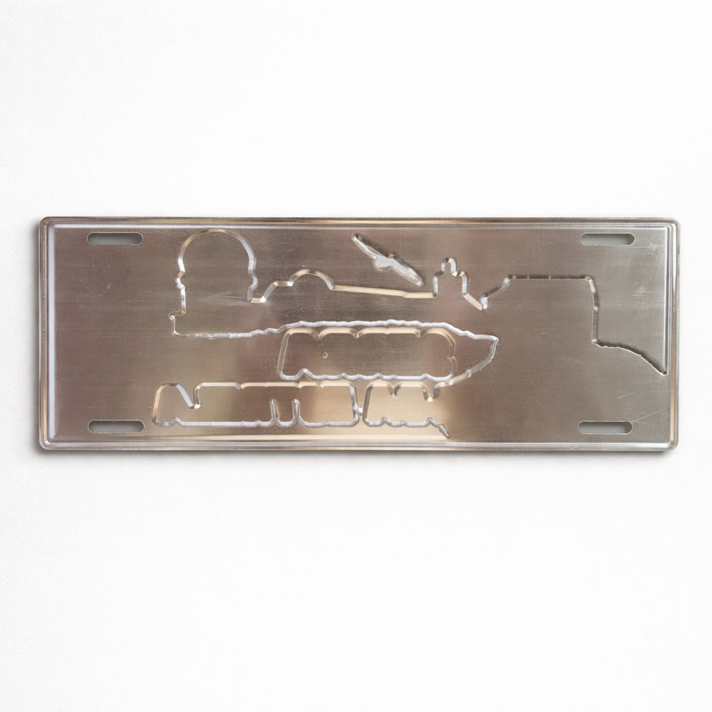 Backside of Serra da Estrela metal souvenir sign showing engraved mountain and building outlines on a metallic surface