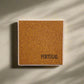A rectangular cork board mounted on a wall with the word "PORTUGAL" printed in black letters in the bottom right corner, serving as a charming souvenir. Subtle shadows fall across the wall and board, suggesting natural light from a nearby window.