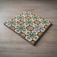This detailed ceramic tile features a vibrant mix of geometric and floral patterns, mainly in shades of white, green, and yellow. The word "PORTUGAL" is highlighted in white, making it a perfect memento for travelers or a unique addition to a cork coaster set.