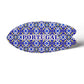This oval-shaped ceramic object is decorated with a colorful mosaic reminiscent of Portuguese azulejo tiles. The word "PORTUGAL" appears prominently in blue uppercase letters in the center. The piece sits on a cork base, creating a soft shadow on the white backdrop.
