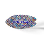 This oval-shaped ceramic object features a colorful mosaic pattern inspired by traditional Portuguese azulejo tiles. The word "PORTUGAL" is prominently written in blue uppercase letters in the center. It sits on a cork base, casting a soft shadow on the white surface.