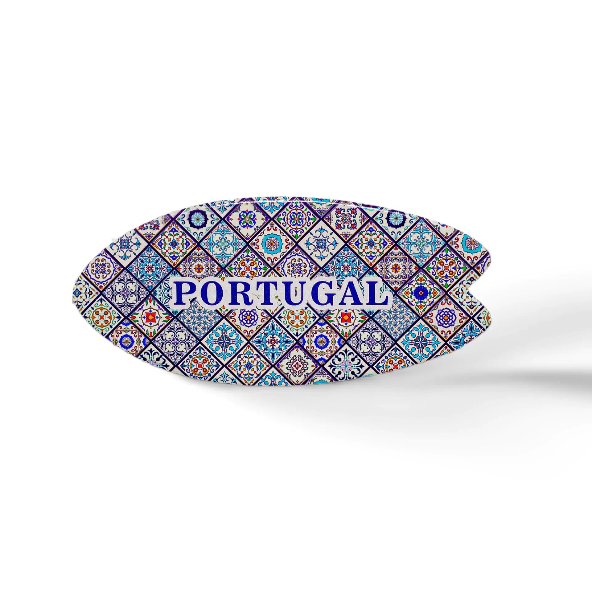 This oval-shaped ceramic object features a colorful mosaic pattern inspired by traditional Portuguese azulejo tiles. The word "PORTUGAL" is prominently written in blue uppercase letters in the center. It sits on a cork base, casting a soft shadow on the white surface.