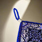 A ceramic tile in a square shape, decorated with a delicate blue and white pattern. The word "Portugal" is centered, framed by a blue braided cord. The tile is supported by a cork base and includes a hanging loop at the top.