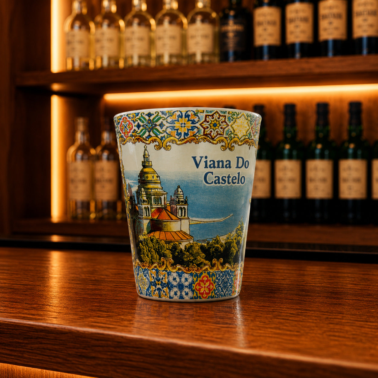 Decorative Viana do Castelo souvenir shot glass featuring Portuguese landmark illustrations and ornate azulejo-inspired artwork on a wooden bar counter