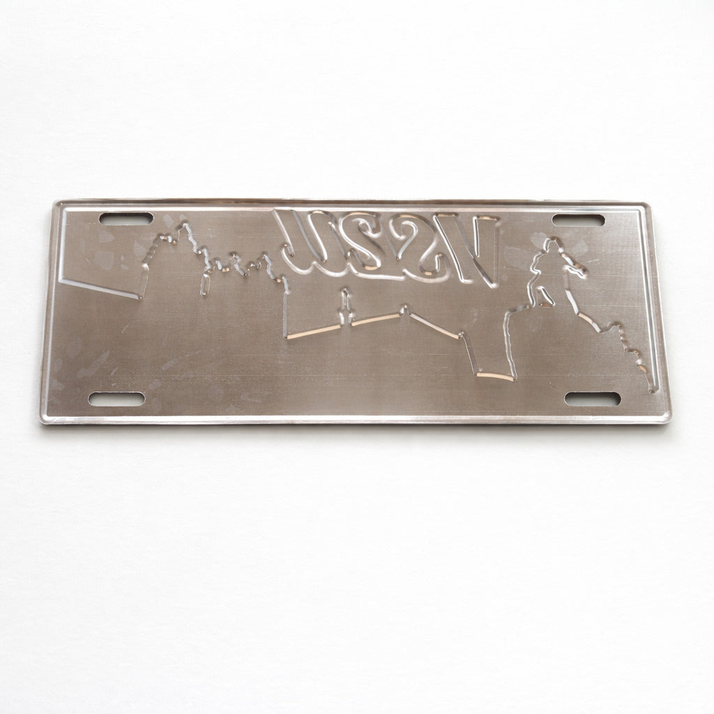 Backside of Viseu metal souvenir sign showing engraved city skyline outlines on a metallic surface