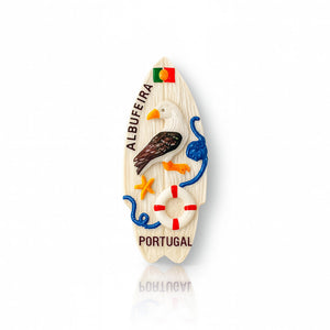 A fridge magnet in the shape of a surfboard with seagull and nautical elements, featuring the Albufeira and Portugal branding.