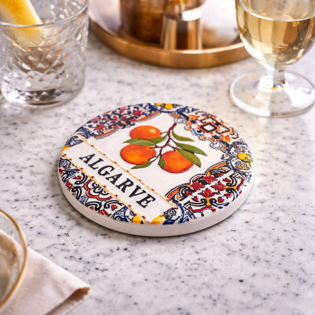Angled view of Algarve ceramic coaster showing detailed tile patterns and orange illustration
