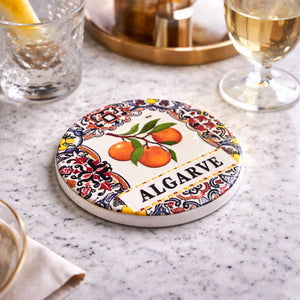 Algarve ceramic coaster with orange design placed on table with drinks in elegant setting