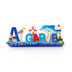 A 3D fridge magnet with the text 'ALGARVE' arranged with symbols such as a seagull, a lighthouse, and a dolphin, against a blue ocean-inspired background.