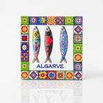 Square Algarve magnet made of resin, featuring three decorative sardines with colorful folk patterns, framed by a border of traditional Portuguese tiles