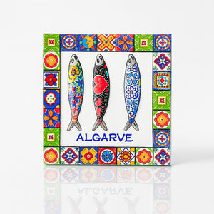 Square Algarve magnet made of resin, featuring three decorative sardines with colorful folk patterns, framed by a border of traditional Portuguese tiles