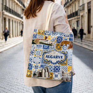 Algarve souvenir cotton tote bag with azulejos pattern carried on shoulder in Portuguese street.