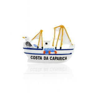 Magnet shaped like a small white fishing boat with yellow ropes, fishing nets, a seagull figure at the front, and “Costa da Caparica” written on the side