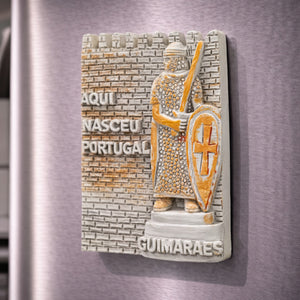 Guimarães souvenir magnet placed on a fridge with medieval warrior relief, shield, sword and “Aqui Nasceu Portugal” text