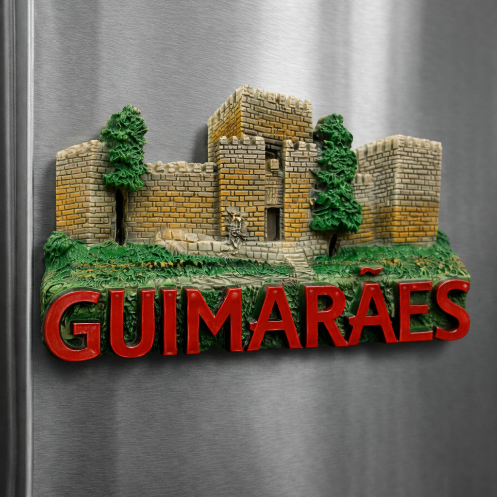 Guimarães Portugal souvenir magnet placed on a fridge featuring a medieval stone castle, historic walls, green landscape details, and raised lettering