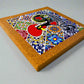 Colorful mosaic artwork with a red circle and geometric patterns on a cork board.