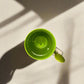 Green mug with a spoon on a light gray surface