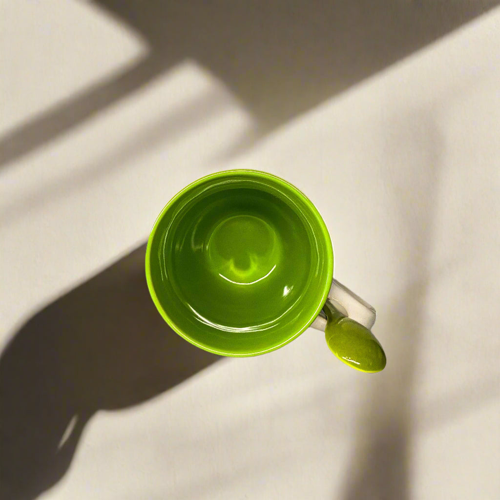Green mug with a spoon on a light gray surface