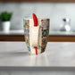 Colorful mug with a red object inside on a white surface