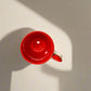 Red mug on a gray surface with a white wall in the background
