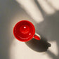 Red mug on a gray surface with a white wall in the background
