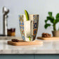 Colorful mug with a pattern and a green straw on a white surface.