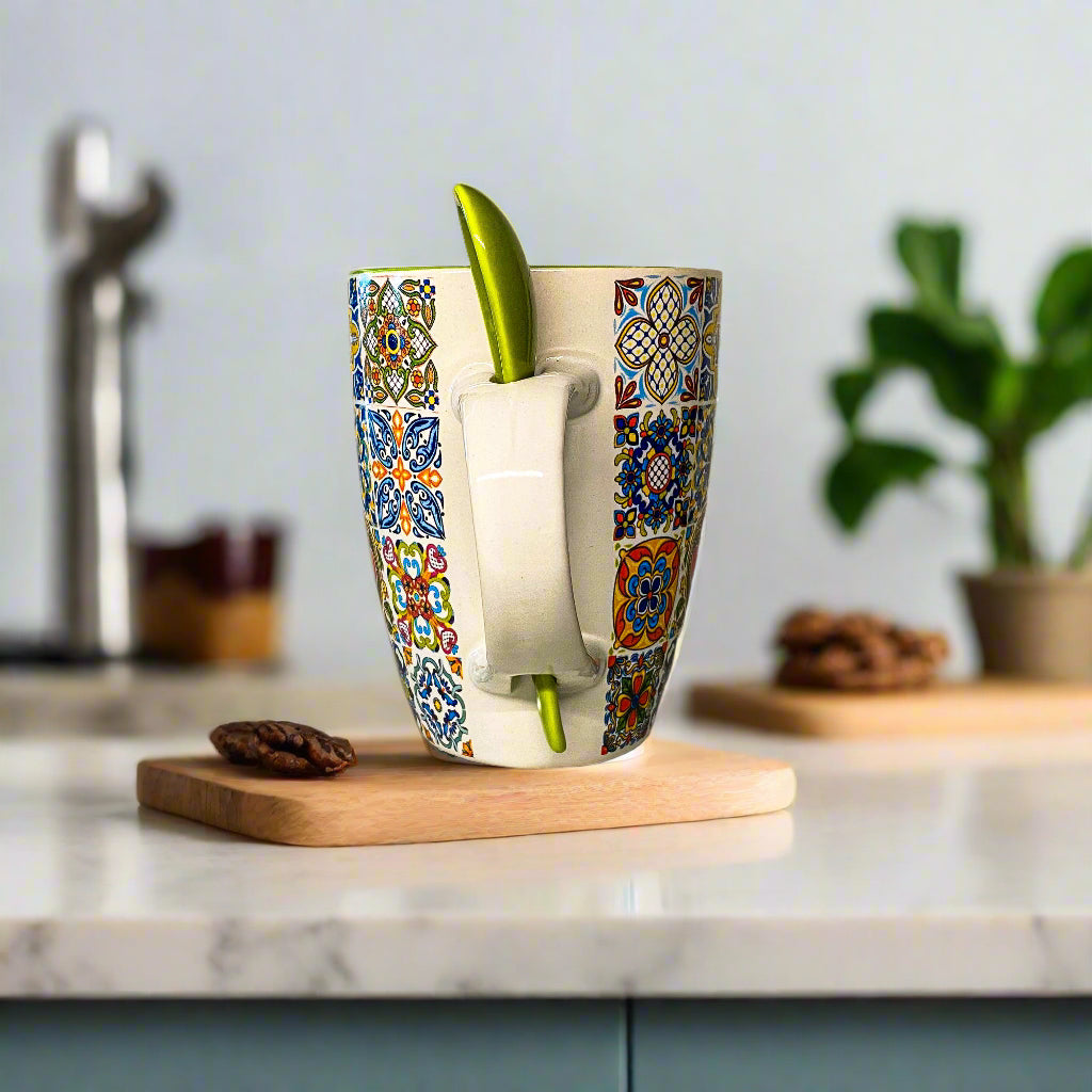 Colorful mug with a pattern and a green straw on a white surface.